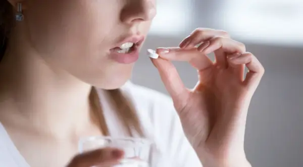 Kobieta bierze tabletkę clindamycin na ból zęba.
