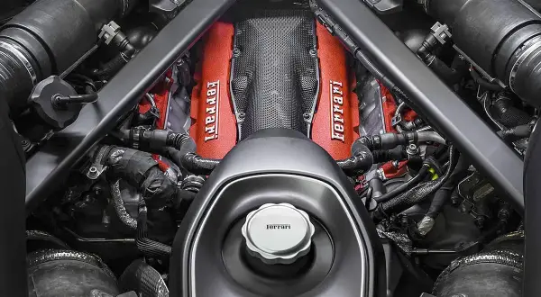 Silnik Ferrari v12, z czerwonymi pokrywami zaworów i charakterystycznym logo, gotowy do pracy.
