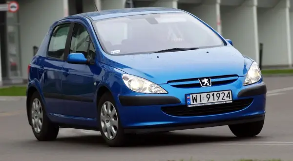 Niebieski Peugeot 307 2.0 HDI z polskimi tablicami WI 91924 jedzie po drodze.