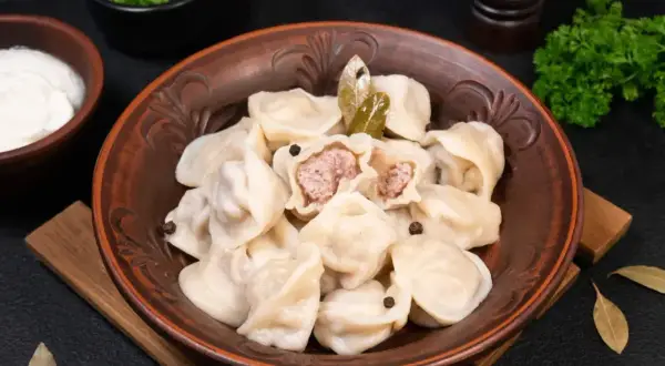 Pielmieni co to? Aromatyczne pierożki z mięsem, podane z kwaśną śmietaną i zieloną pietruszką. Pyszne danie!