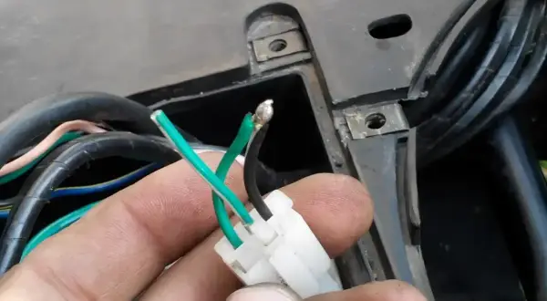 Ręka trzyma luźne przewody zielony i czarny, które mogą być przyczyną, że skuter kręci ale nie odpala 4t.