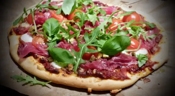 En läcker bresaola pizza med körsbärstomater, ruccola och färsk basilika.