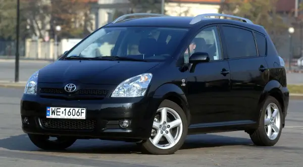 Czarny Toyota Verso z polskimi tablicami WE 1606F zaparkowany na ulicy.