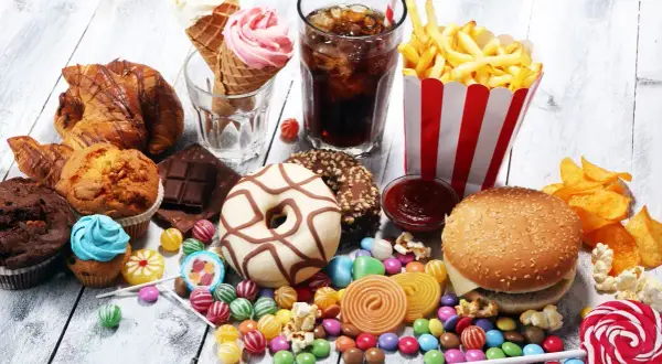 En överflöd av ultraprocessad mat: hamburgare, pommes frites, donuts, godis, glass, läsk och bakverk.