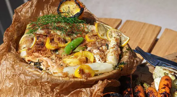 Fisk i folie med citron, dill och grönsaker, serverad med grillade morötter och fänkål.