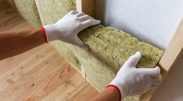 Pose d'isolant minéral dans une structure de mur intérieur. L'épaisseur de l'isolation est visible, assurant une bonne performance thermique.