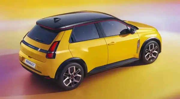Nowe Renault 5 w jaskrawym żółtym kolorze z czarnym dachem i czerwonymi akcentami, prezentuje nowoczesny design.