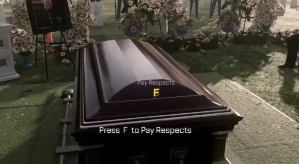 Na cmentarzu trumna, obok zdjęcie zmarłego. Na trumnie napis "Press F to Pay Respects".
