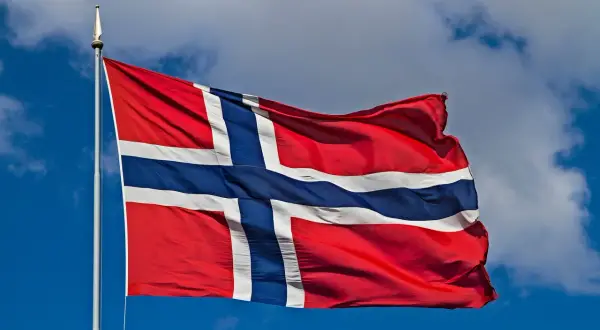 Norwegia praca dla kobiet: flaga powiewa na tle błękitnego nieba z chmurami.