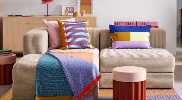 Gemütliches Wohnzimmer mit Sofa, bunten Kissen und Decken. Perfekt für die erste eigene Wohnung, um sich einzurichten.