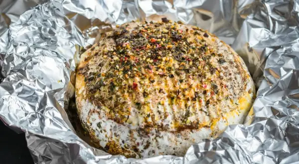 Pyszny camembert z grilla, otulony folią aluminiową, posypany ziołami i przyprawami. Idealny na letnie wieczory.