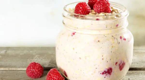 Overnight oats med proteinpulver och hallon i en glasburk, redo för en proteinrik frukost.