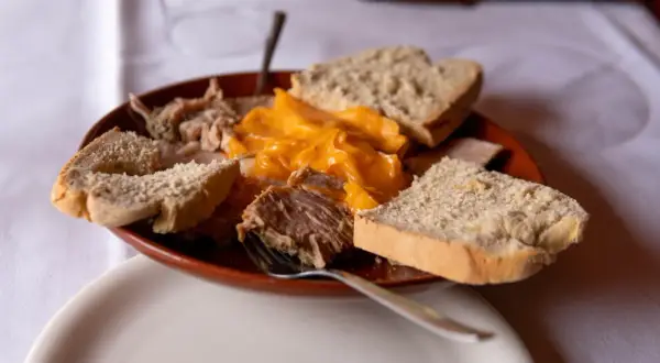 Plato de lomo en manteca con pan rústico y una salsa cremosa de queso.