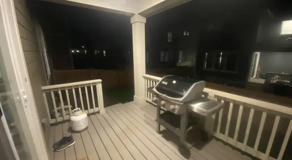 En gasolgrill under taket på altanen, redo för sommarens grillkvällar.