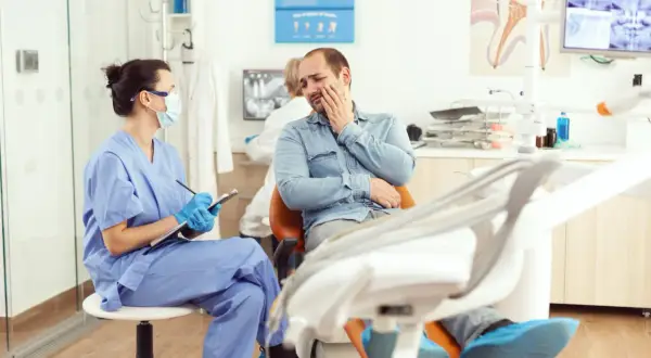 Pacjent u dentysty skarży się na ból, być może krwiak po znieczuleniu. Pielęgniarka notuje objawy.
