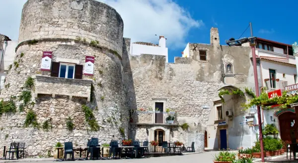 Antica torre del castello di Peschici, con tavoli all'aperto di un ristorante.