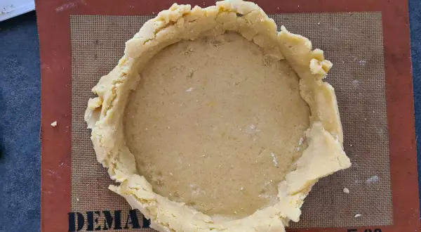 Pâte à gâteau basque prête à être garnie, posée sur un tapis Silpat.