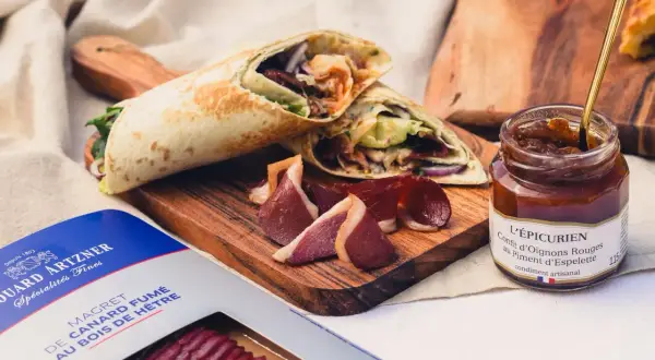 Wrap de magret de canard fumé, servi avec des tranches de canard et un confit d'oignons rouges.