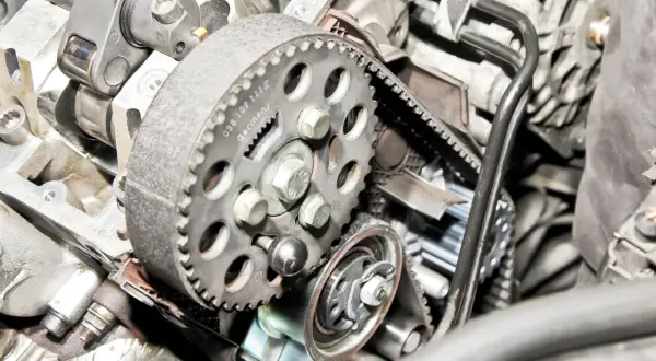Widok na mechanizm rozrządu w samochodzie: zębatka, pasek i napinacz.