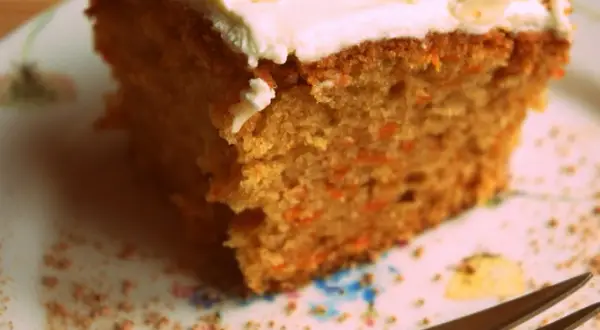 Wilgotne ciasto marchewkowe z puszystą polewą z mascarpone, posypane płatkami migdałów. Idealne na deser.