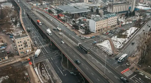 Widok z lotu ptaka na estakadę Kwiatkowskiego z ruchem samochodowym, budynkami i terenami zielonymi.