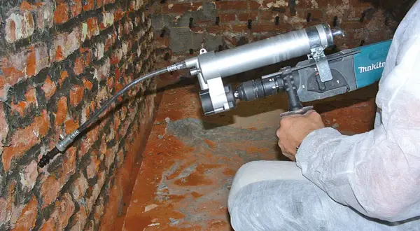 Mauerwerk Injektion selber machen: Gerät zur Rissverpressung an einer Ziegelwand.