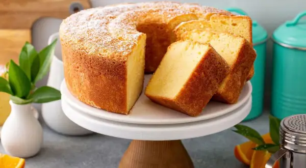 Puszyste ciasto na niedzielę, oprószone cukrem pudrem, z kilkoma kromkami obok. Idealne na rodzinne popołudnie.