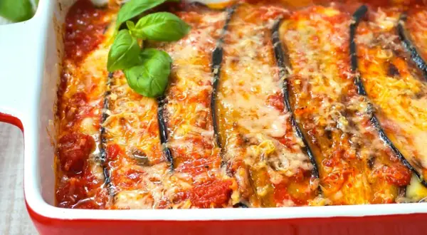 Berenjenas a la parmesana recién horneadas, burbujeantes y doradas, con queso fundido y un toque de albahaca fresca. ¡Un plato italiano irresistible!
