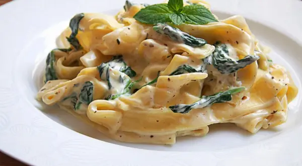 Pappardelle w kremowym sosie ze szpinakiem i mascarpone, udekorowane listkami mięty. Pyszne danie, które zachwyci każdego.