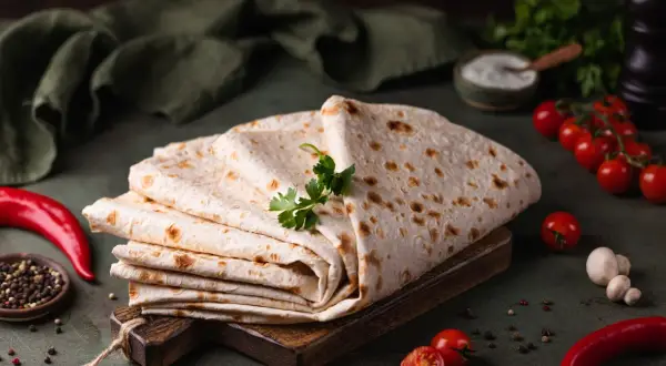 Stos cienkiego, puszystego lawaszu, ozdobiony natką pietruszki, obok pomidorków, papryczki chili i pieprzu. Idealny do wrapów.
