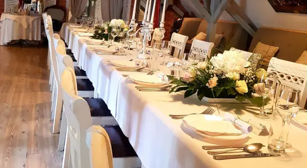 Elegancko nakryty stół w restauracji, gotowy na przyjęcie. Zastanawiasz się, ile trwają chrzciny w restauracji? Zazwyczaj to kilka godzin, w zależności od programu.