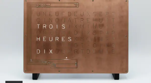 Horloge murale au design industriel, avec une plaque de cuivre gravée de lettres formant des mots. Une lettre métal unique pour un style épuré.