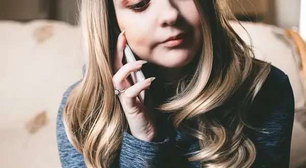 Kobieta rozmawia przez telefon, szukając informacji, jak włączyć roaming T-Mobile kodem.