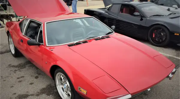 En röd De Tomaso Pantera bil med uppfälld huv. Bredvid står en svart bil med uppfällda dörrar.