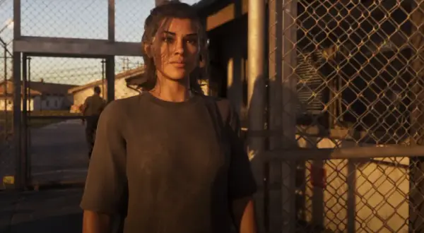 Lucia z GTA 6 stoi przed bramą, za nią widać budynki i strażnika.