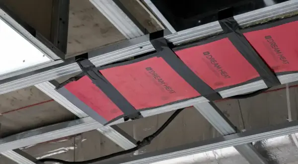 Instalacja grzejnika na podczerwień w suficie podwieszanym. Wady montażu widoczne na taśmie mocującej.