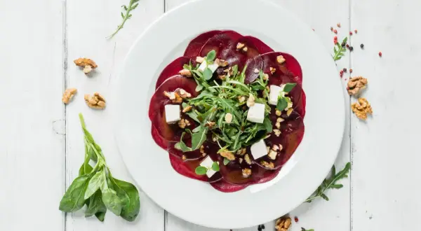Eleganckie carpaccio z buraka z fetą, orzechami i rukolą. Idealny przepis na lekki i zdrowy posiłek.