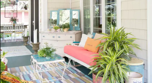 Porches sencillos y bonitos con un sofá coral, plantas exuberantes y un tocador vintage.