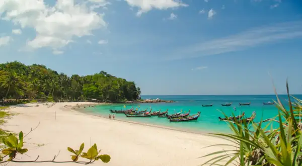 Piękne phuket plaże z turkusową wodą, białym piaskiem i łodziami dryfującymi na morzu.