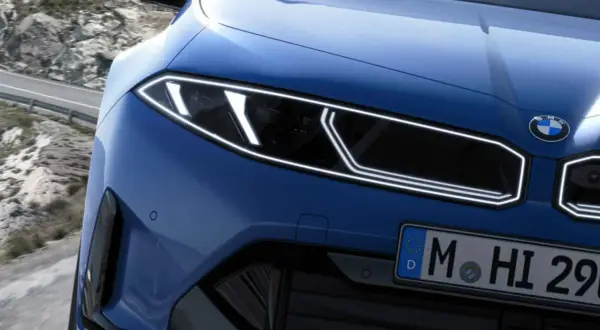 El frontal de un BMW azul eléctrico con tracción trasera, listo para devorar curvas en una carretera de montaña.