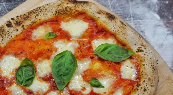 Une Margherita parfaite, symbole de la recette pizza italienne traditionnelle. Sauce tomate, mozzarella fondante et basilic frais sur une pâte dorée.