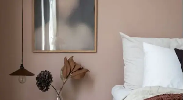 Un angolo letto con pareti color malva, un quadro astratto e un vaso con fiori secchi. Gli abbinamenti verde malva colore creano un'atmosfera rilassante.