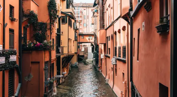Enge Gasse mit Kanälen und pastellfarbenen Häusern in Bologna. Wie viele Tage würde man hier verbringen wollen?