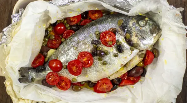 Orata al cartoccio con pomodorini, olive e capperi, cotta in forno.