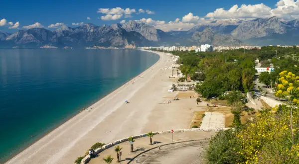 Piękna plaża i turkusowe morze w Turcji, idealne miejsce na wakacje. W tle góry i miasto.