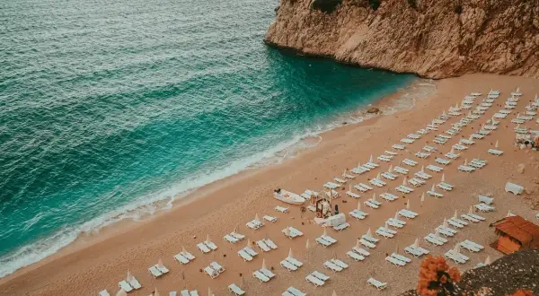 Piękna plaża z rzędami leżaków i turkusową wodą. Idealne miejsce, by zastanowić się, gdzie do Turcji na wakacje.