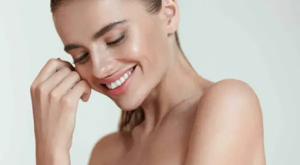 Donna sorridente con pelle luminosa, un esempio di come mantenere la pelle giovane e radiosa.