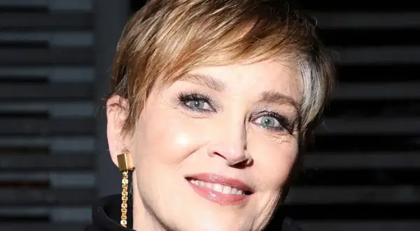 Mujer de 60 años con cortes de pelo corto modernos, luciendo un pendiente dorado y una sonrisa radiante.