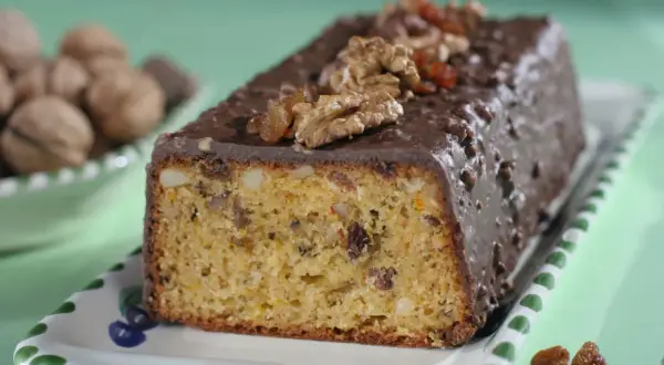 Pyszna babka z orzechami włoskimi, oblana czekoladą i ozdobiona bakaliami.