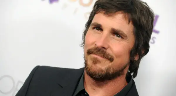 Christian Bale z brodą i w garniturze, znany z wielu świetnych christian bale filmów.